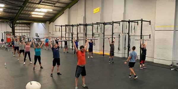 group of athletes life a barbell over their heads